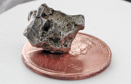 Campo del Cielo meteorite fragment sitting on a penny